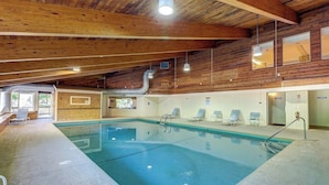 An indoor swimming pool with wooden beams, clear water, and lounge chairs. - Resort condo with 3 pools, sports courts, & convenient ski access (Warren)