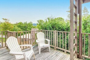 Eine Holzterrasse mit zwei weißen Adirondack-Stühlen und einem Hollerleger.