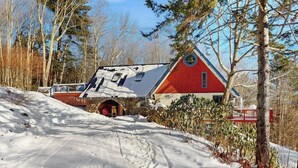 En röd byggnad med en entré av sten, omgiven av snö och träd.