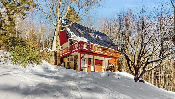 Ett snötäckt landskap med ett hus som har en röd balkong och ett sluttande tak.