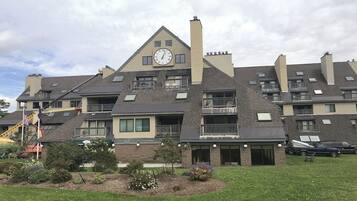 Un edificio residencial de varios pisos con balcones, un reloj y una chimenea.