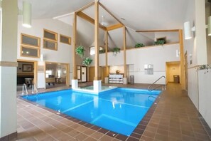An indoor swimming pool with a tiled floor, wooden beams, and potted plants. - Top-Floor Condo, ski-home trail, w/ fireplace, balcony, w/d, hot tub, pool, wifi (Killington)