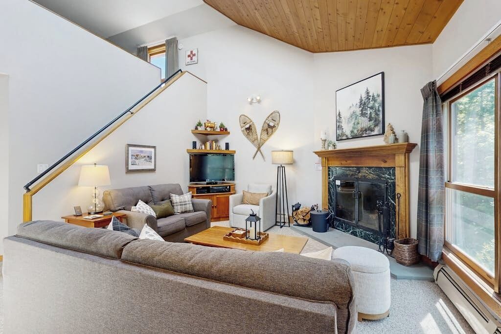 A living room with a sofa, coffee table, fireplace, and a staircase.