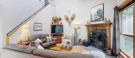 A living room with a sofa, coffee table, fireplace, and a staircase.