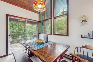 Zona pranzo con tavolo in legno, panche e vista all'esterno tramite ampie finestre.