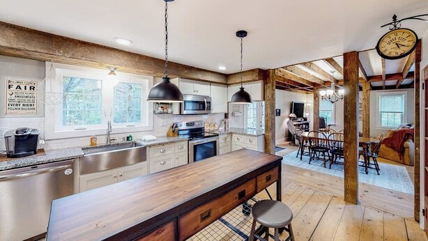 A modern kitchen with wooden beams, a large island, and pendant lighting. - Charming dog-friendly home with private deck, firepit, washer/dryer, & cable (Wallingford)