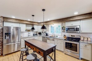 A modern kitchen with stainless steel appliances, a wooden island, and pendant lighting.