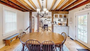 A dining area with a wooden table and chairs, a chandelier, and a view into the kitchen. - Charming dog-friendly home with private deck, firepit, washer/dryer, & cable (Wallingford)