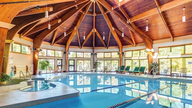 Ein großes Hallenbad mit Holzbalkendecke und mehreren Fenstern.