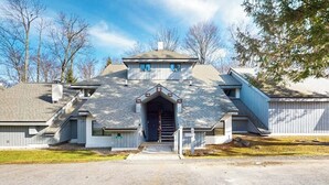 Ein zweist öckiges Haus mit Mittelbau, einer kleinen Veranda und einer Garage.