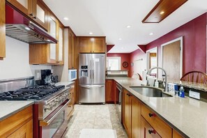 A kitchen with wooden cabinets, stainless steel appliances, a gas stove, and a sink. - Cozy, updated riverfront home with gas stove & AC (Warren)