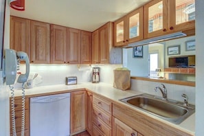 A kitchen with wooden cabinets, a built-in dishwasher, a sink, and a telephone. - Relaxing Ski Condo with Pools and Entertainment - Near Ski Access (Warren)