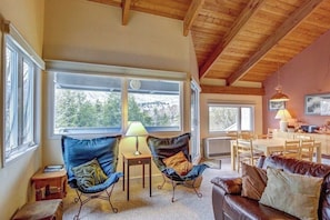 A cozy room with a wooden ceiling, large windows, a brown leather sofa, two armchairs, and a dining table. - Relaxing Ski Condo with Pools and Entertainment - Near Ski Access (Warren)