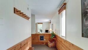 A narrow hallway with wooden walls, a bench, a small table with a lamp, and a window. - Lovely condo near skiing with 3 pools, sauna, fitness room & balcony (Warren)