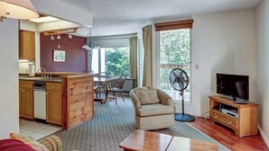 A compact living space with a kitchenette, dining area, and a TV stand. - Lovely condo near skiing with 3 pools, sauna, fitness room & balcony (Warren)