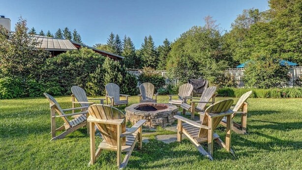 A circular outdoor seating area with wooden chairs and a central fire pit.