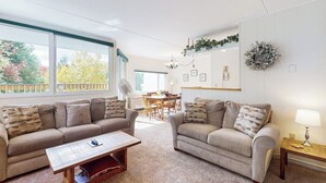 A living room with two sofas, a coffee table, and a dining area in the background.