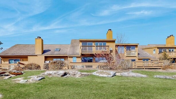 A multi-story building with a flat roof, large windows, and a balcony. - Saltbox townhome with views & fireplace - near Quechee Club, golf, & skiing (White River Junction)