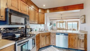 A kitchen with wooden cabinets, a stainless steel stove, a microwave, and a dishwasher. - Saltbox townhome with views & fireplace - near Quechee Club, golf, & skiing (White River Junction)