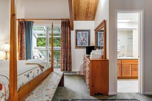 A bedroom with a four-poster bed, a wooden dresser, and a view of the bathroom. - Convenient Condo with Pool - Mountain Views, Near Town & Slopes (Warren)