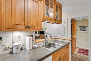 A kitchen with wooden cabinets, a stainless steel sink, and a countertop. - Convenient Condo with Pool - Mountain Views, Near Town & Slopes (Warren)