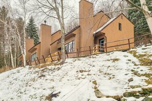 A wooden cabin with a steep roof, large windows, and a wooden deck.