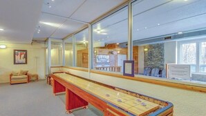 Ein Shuffleboard-Tisch in einem Raum mit großen Fenstern, einer Couch und einem Schild, das eine Kneipe anzeigt.