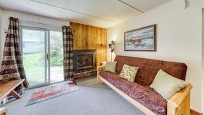 Ein gemütliches Wohnzimmer mit einer Couch, einem Kamin und einem großen Fenster.