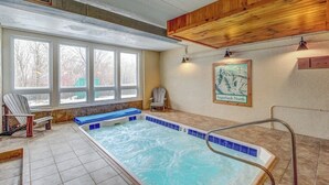 Ein Wellnessbereich mit Whirlpool, zwei Stühlen, einem Fenster und einem gerahmten Bild an der Wand.