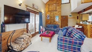 Ein gemütliches Wohnzimmer mit Fernseher, Karosostaschen, einem Couchtisch und einem Kamin.