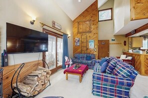Ein gemütliches Wohnzimmer mit Fernseher, Karosostaschen, einem Couchtisch und einem Kamin.