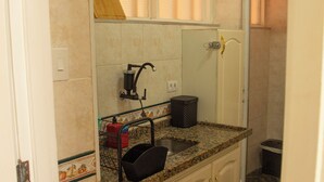 A bathroom with a sink, mirror, and tiled walls. - Florida in Guarujá. Cozy apartment with ocean view. Pets allowed! (Guarujá)