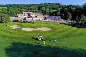 Ein Golfplatz mit Bunkern, einem Clubhaus und einem Gebäude mit Walmdach.