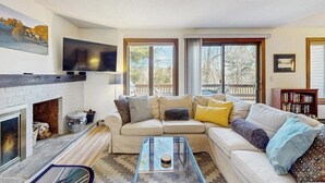 Una sala de estar con chimenea, sofá, mesa de centro y televisor.