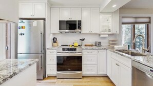 Una cocina moderna con armarios blancos, electrodomésticos de acero inoxidable y encimera de granito.
