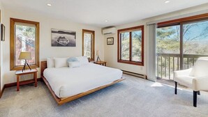 Un dormitorio con una cama grande, una silla, una mesita de noche y una ventana con vistas.