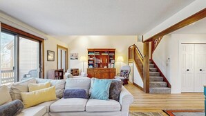 Una sala de estar con un sofá, una estantería de madera, una escalera y una puerta.