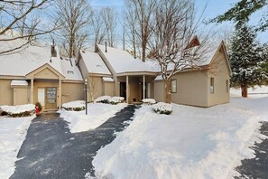 A two-story house with a snow-covered driveway and a small detached garage.