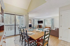 A dining area with a wooden table, chairs, and a television.