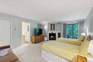 Een slaapkamer met twee bedden, een televisie, een open haard en uitzicht op het landschap.
