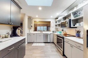 A modern kitchen with stainless steel appliances, grey cabinetry, and a skylight. - End unit townhome near golf & ski - walk to Quechee Club - views & fireplace (Hartford)