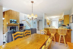 A dining area with a wooden table and chairs, a kitchen with wooden cabinets, and a staircase leading to another level. - Deere Run townhouse with private sauna, jetted tub & AC - pool & tennis (Hartford)
