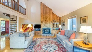 A spacious living room with a fireplace, two sofas, a coffee table, and a large rug. - Quechee Ski Area condo on the ski trail - mountain views & AC (Hartford)