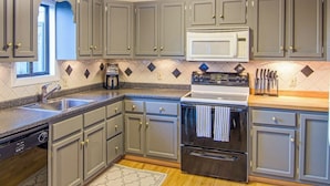 A kitchen with grey cabinets, a microwave, a stove, and a dishwasher. - Quechee Ski Area condo on the ski trail - mountain views & AC (Hartford)