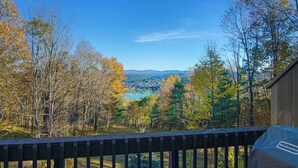 A deck with a view of a forest and a lake. - Quechee Ski Area condo on the ski trail - mountain views & AC (Hartford)