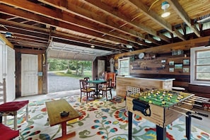 A cozy room with a wooden ceiling, a foosball table, a dining table, and chairs.