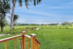 A grassy outdoor area with a wooden deck and chairs.