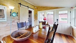 A wooden interior with a dining table, chairs, a bowl, candles, and a lamp. - Historic home on 1 acre with snowmobile trails in backyard & mountain views (Waitsfield)