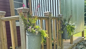 A wooden deck with metal planters holding flowers. - Historic home on 1 acre with snowmobile trails in backyard & mountain views (Waitsfield)