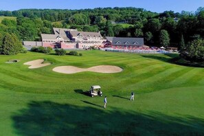 Ein Golfplatz mit Clubhaus, Sandbunkern und einem Golfwagen.